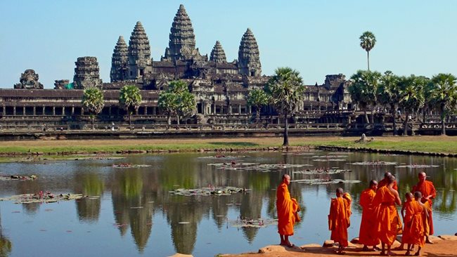 Будистки монаси си почиват пред известния храмов комплекс Ангкор Ват в Камбоджа.
