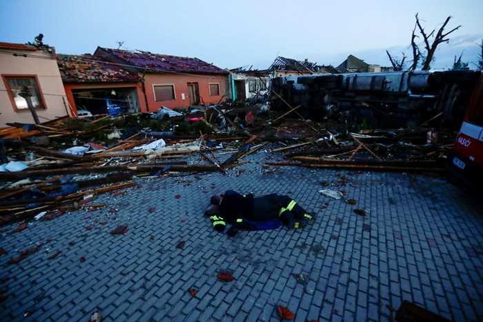 Изтощен спасител си почива сред развалините в опустошеното село Моравска Нова Вес.