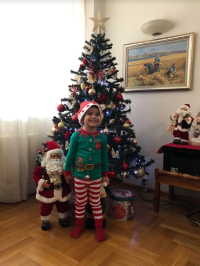 2-годишният Максим от Ботевград усмихнато позира пред елхата, държейки за ръка Дядо Коледа и нетърпеливо чака коледните подаръци