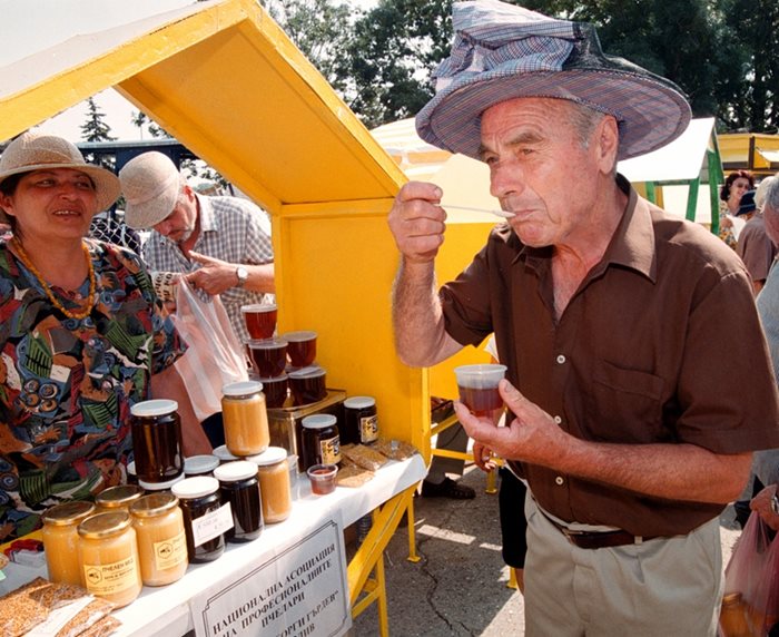 Възрастен мъж опитва мед на фермерски пазар. Плановете на държавата са да направи специални пазари, на които стари хора ще продават собствена продукция.