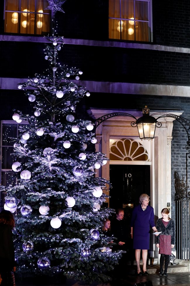 Британският пречмиер Тереза Мей се радва на елхата пред резиденцията й на "Даунинг стрийт" 10 в Лондон