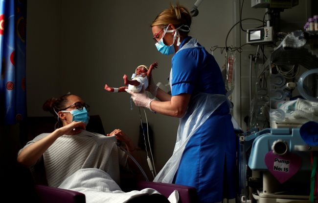Медицинска сестра с маска за първи път дава недоносено бебе на майка му в английския град Бърнли.