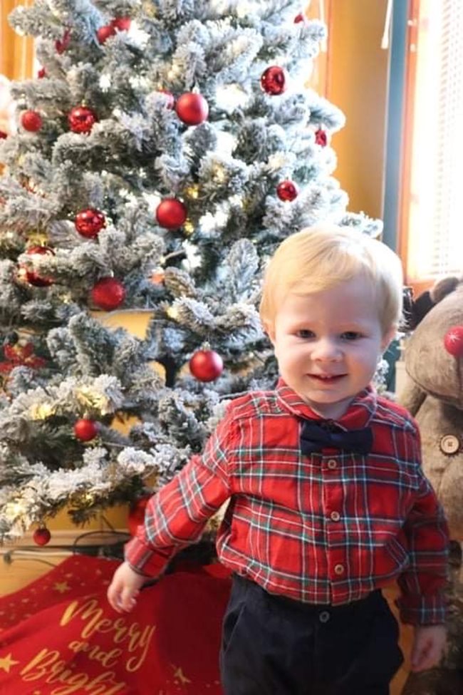 Дамян Бонев е само на година и 9 месеца, но вече знае как се носи папийонка. Застанал до празничната елха вкъщи, той позира усмихнато за радост на всички, а не само на щастливите мама Стела и татко Бойко.