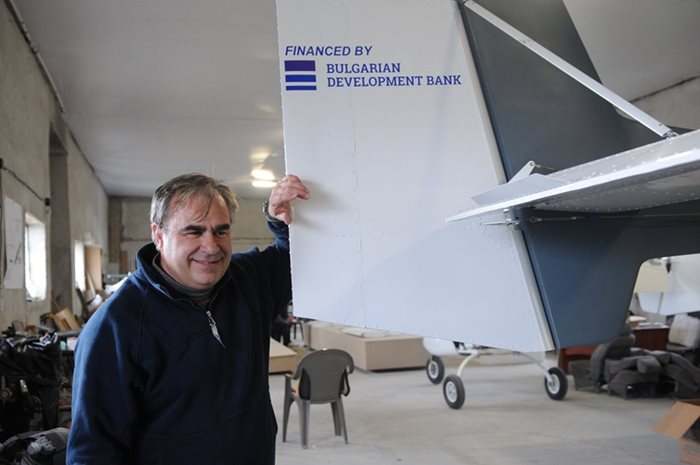 Тони Илиев до опашката на самолета, брандирана с логото на Българската банка за развитие